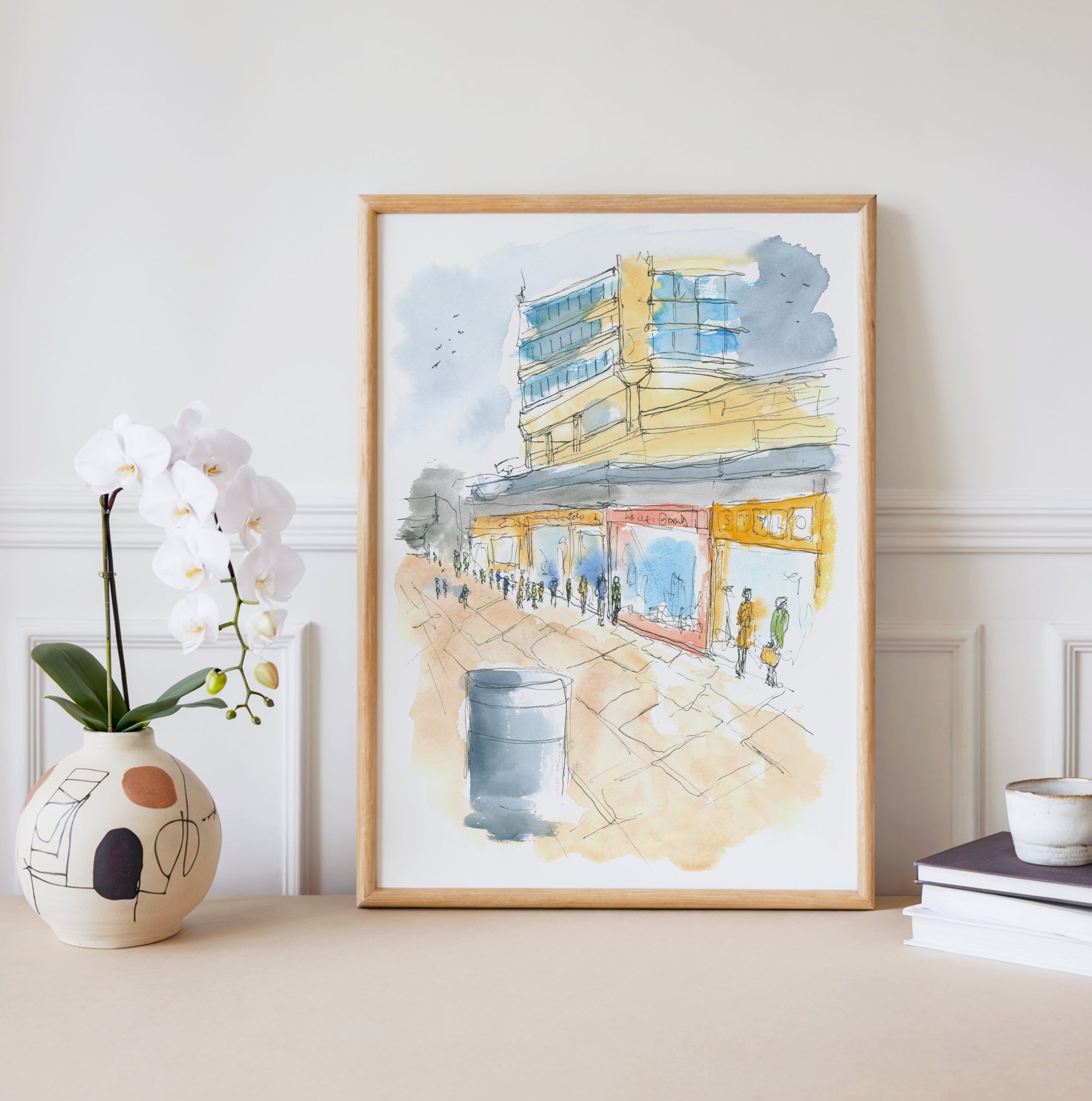 Framed watercolour print of 1990s Sunderland town centre displayed on a wall, capturing the bustling high street and iconic tower blocks of a North East city in its prime
