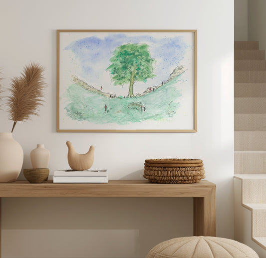 Framed watercolour print of the Sycamore Gap Tree displayed on a wall, showing the rich colours and detail of the artwork in a home setting